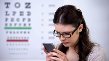 Akıllı telefonu tutan gözlüklü güzel kadın, görme üzerinde teknoloji etkisi