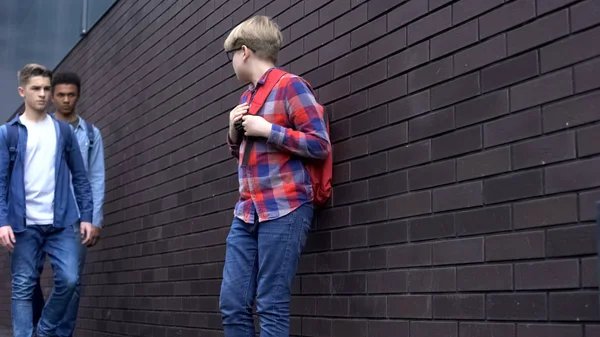 Korkmuş çocuk lise öğrencilerine bakıyor, zorbalık kurbanı sindirilmiş