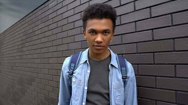 Afro-american schoolboy looking mockingly into camera, aggressive adolescent