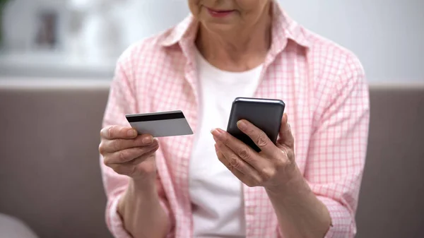 Seniorin gibt Kreditkartennummer auf Smartphone ein und bezahlt Rechnungen online — Stockbild Seniorin Gibt Kreditkartennummer Auf Smartphone Ein Und Bezahlt Rechnungen Online — Stockfoto