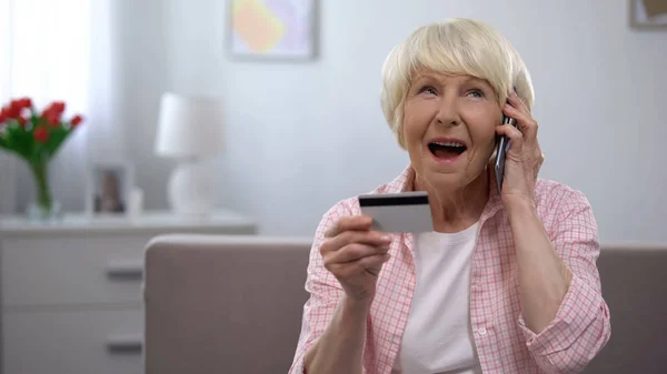 Alte Frau mit Kreditkarte und sprechendem Telefon, Bankprogramme für alte Menschen — Stockbild Alte Frau Mit Kreditkarte Und Sprechendem Telefon Bankprogramme Für Alte — Stockfoto