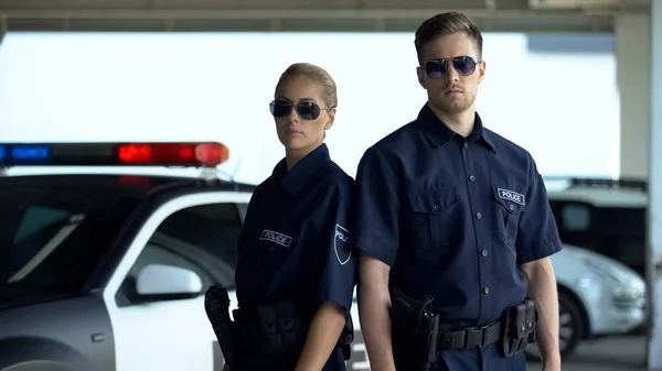 パトカーの近くに立ってサングラスをかけた自信のある警官と男 勤務中 — ストック写真