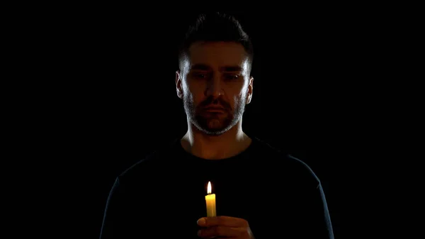 黒い背景にろうそくを持つ絶望的な男 希望の象徴 悲しみの儀式 — ストック写真
