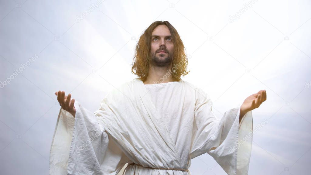 Jesus raising hands to heaven on illuminated background, Resurrection holiday