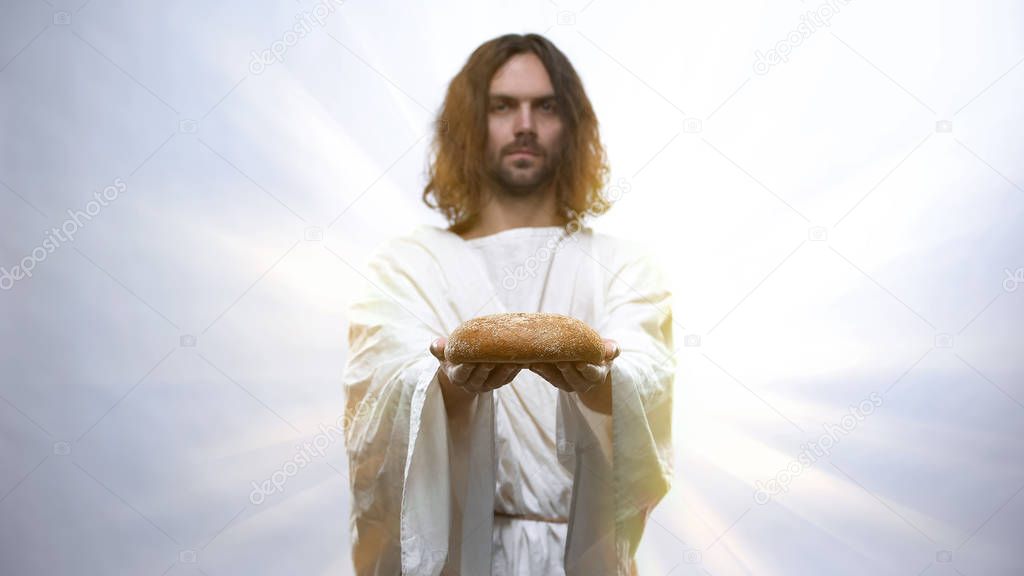 Jesus holding bread on illuminated background, sacramental food in religions