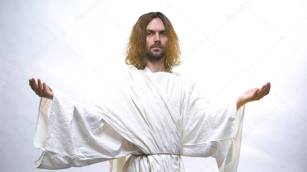 Good God in white robe looking at camera, raising hands to give hope, blessing