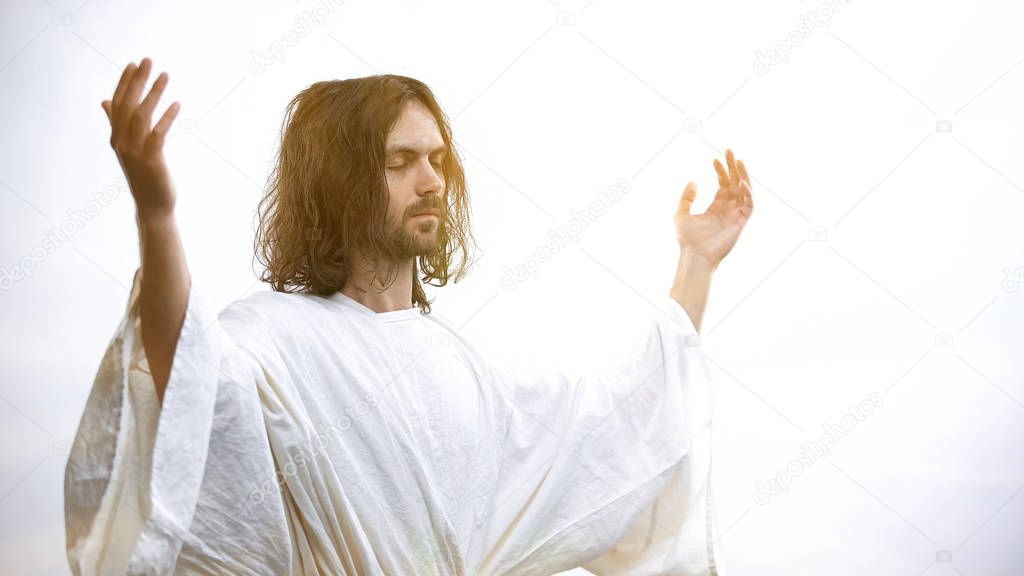 Jesus raising hands illuminated with light, resurrection and ascension of God