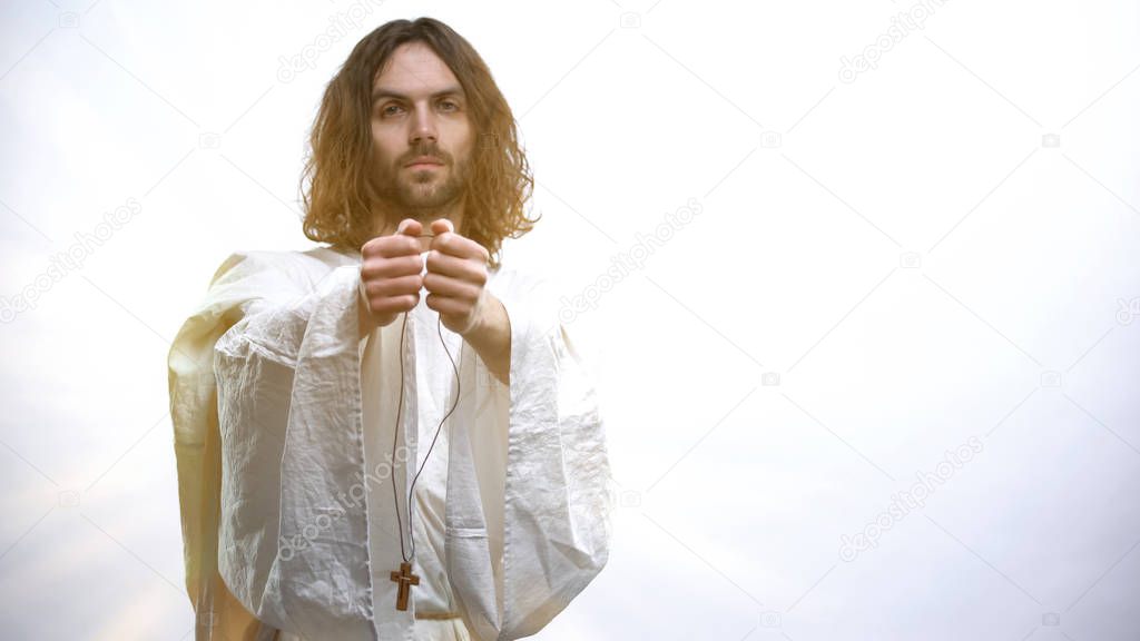 Prophet in white robe holding out cross to camera, religious conversion, baptism