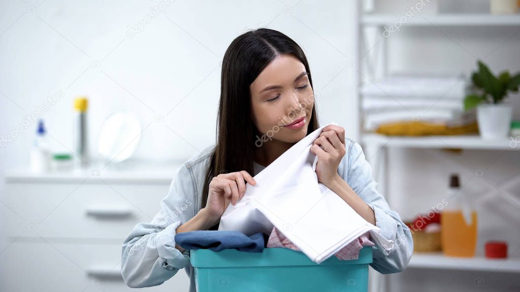 Woman smelling clean fresh linens and smiling at camera, fabric softener