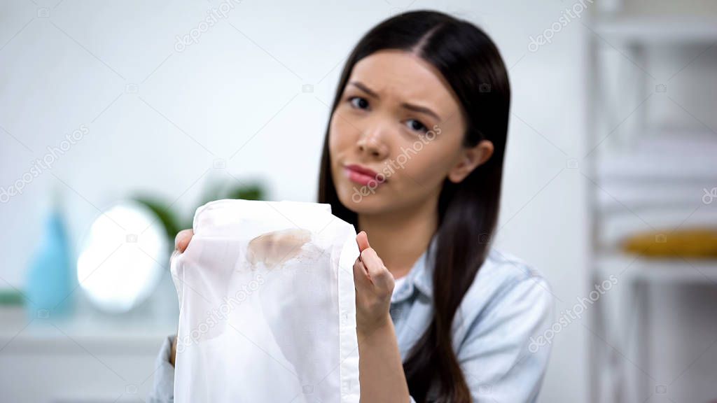 Sad asian housewife showing coffee stain on shirt, bad-quality laundry service