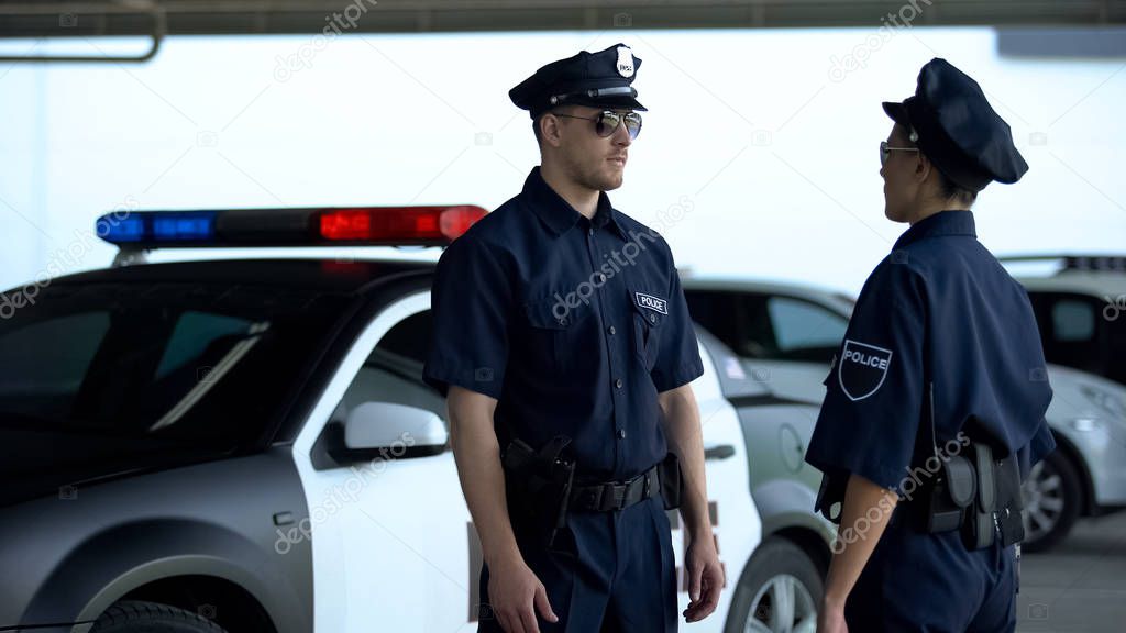 Two serious police officers communicating on parking lot, patrolling district