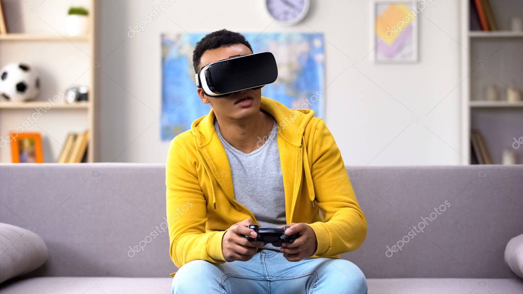 Emotional mixed-race guy in VR headset playing video game, reality simulation