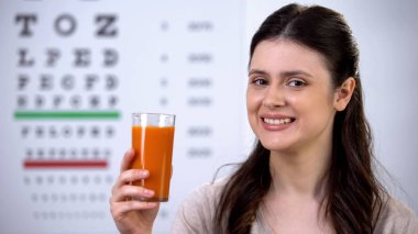 Mutlu kadın sağlıklı taze havuç suyu içme, arka planda göz grafiği, vizyon