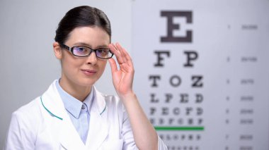 Gülümseyen kadın optometrist gözlük ayarlama ve kamera, profesyonel arıyorum