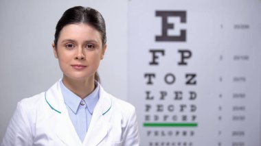 Profesyonel kadın oculist göz grafik arka plan karşı kamera bakıyor