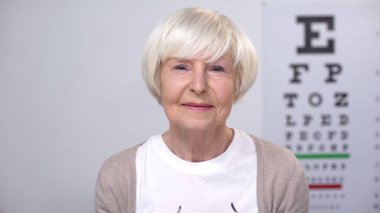Mutlu yaşlı kadın görme muayenesi, mükemmel görme kamera bakıyor