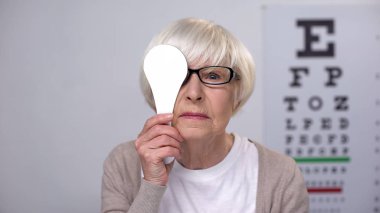 Female retiree in glasses closing eye and shaking head, age related diseases clipart