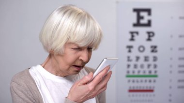 Senior woman with poor vision using smartphone, rejecting to wear eyeglasses clipart