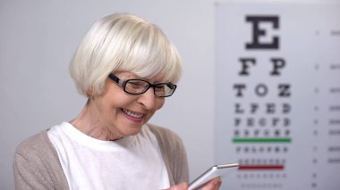 Emekli bayan gözlük gülümseyen ve akıllı telefon, görme geliştirme okuma