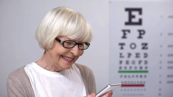 Rentnerin Mit Brille Lächelt Und Liest Auf Smartphone Sehverbesserung — Stockfoto