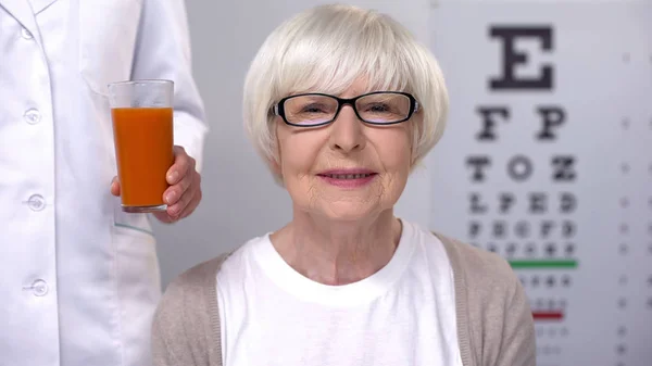 Opticien Geeft Verse Wortel Sap Aan Happy Aged Lady Behoud — Stockfoto