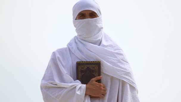Muslim med dolt ansikte kramas Koran tätt, radikal islamisk tro, sharia — Stockvideo