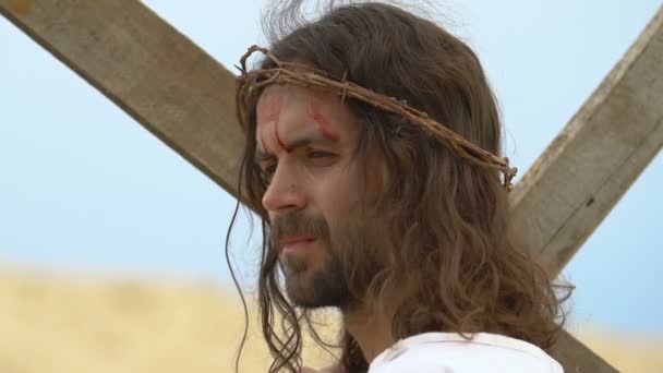 Христос с окровавленной головой, держащий крест, смотрящий в камеру, священная жертва — стоковое видео