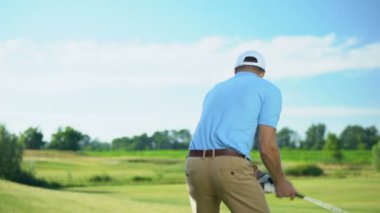 Tecrübeli golf oyuncusu sahada beraberlik pozisyonunda topa vuruyor, geri görüş