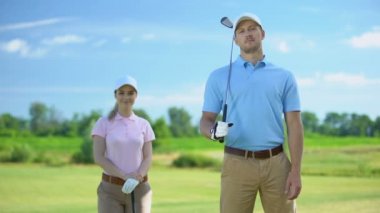 Yakışıklı golf eğitmeni ve kulüpleri kamera, spor gülümseyen kadın acemi