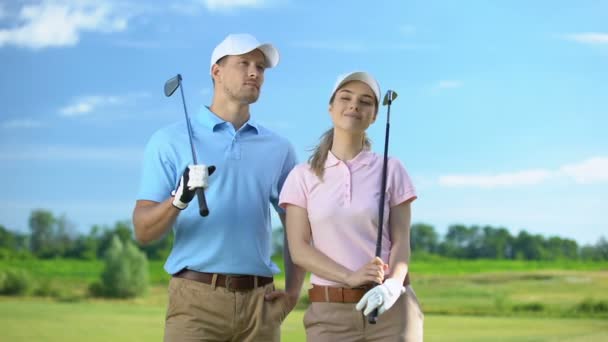 Уверенные игроки в гольф среди мужчин и женщин с клюшками, смотрящими на поле, спортивную игру — стоковое видео