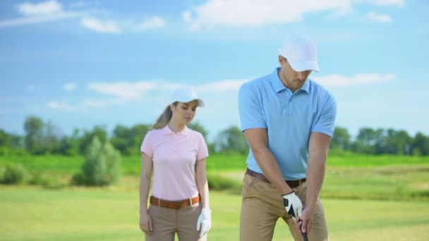 Hombre en ropa deportiva golpeando pelota pareja femenina regocijo juego de golf victoria, deporte — Vídeo de stock