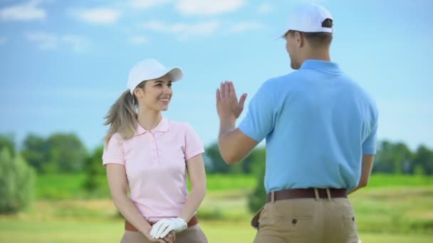 Cheerful female golfer with club giving high-five sport coach, teamwork concept — Stock Video