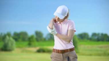 Spor travması sonrası ağrılı dirseğe masaj yapan spor giyimli kadın golfçü, sağlık