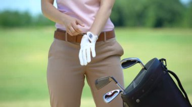 Profesyonel kadın golf oyuncusu eldiven giyen ve kulüp alarak, oynamaya hazır