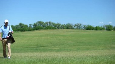 Mutlu erkek golfçü oyun, hobi sonra kulüpleri çanta ile yeşil sahada yürüyüş