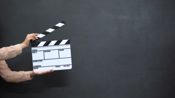 Vrouwelijke handen met behulp van klapper tegen zwarte achtergrond, schieten films — Stockvideo