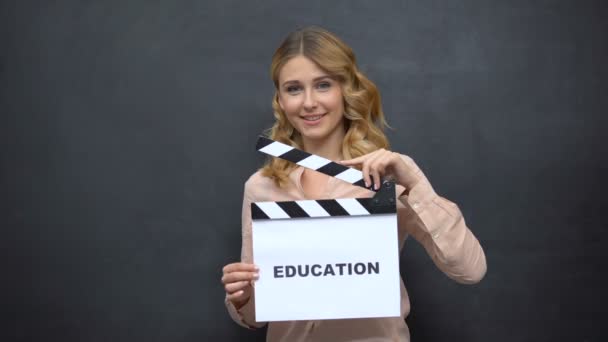 Menina usando clapperboard com palavra Educação, início do ano letivo, graduação — Vídeo de Stock