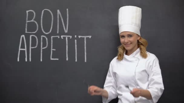 Chef sosteniendo cuchillo y tenedor, posando cerca de Bon Appetit Frase francesa, gastronomía — Vídeos de Stock