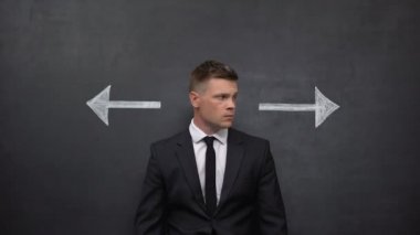 Kafası karışmış işadamı okların arasında duruyor, doğru yönü seçiyor, kar