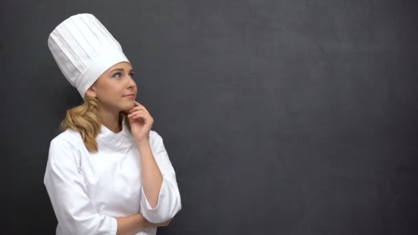 Старший повар в поисках вдохновения прикасается подбородком к черной доске — стоковое видео