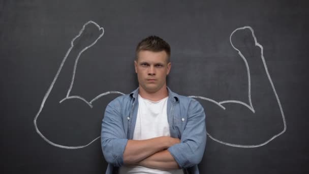 Poważny człowiek stoi na tle z pomalowane biceps, Kulturystyka — Wideo stockowe