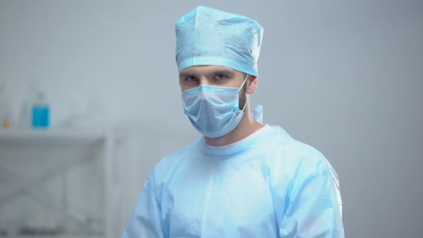 Smiling surgeon taking off medical face mask after successful operation, work — Stock Video