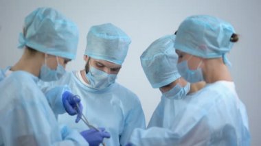 Ameliyathanede çalışan profesyonel cerrah ekibi, hemşirekameraya gülümsüyor
