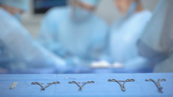 Mãos de assistente cirurgião tomando equipamento médico estéril da mesa, clínica — Vídeo de Stock