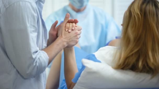 Close-up de homem segurando mão esposa para apoio durante empurrar para dar à luz — Vídeo de Stock