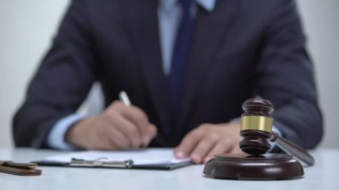 Erkek hakim bloküzerinde tokluk vurarak belge imzalayarak, mahkeme ceza belirler