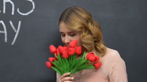 Frau lächelt und riecht Tulpen, glücklicher Muttertag auf Tafel, gratuliere — Stockvideo