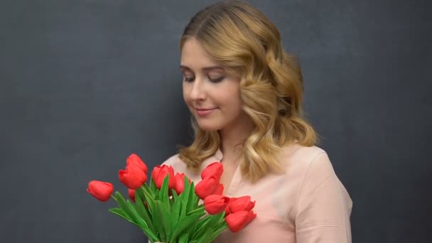 Pretty lady holding bunch of tulips isolated on blackboard background, allergy — Stock Video