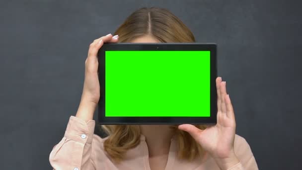 Woman holding prekeyed tablet, hiding face behind, place for advertisement — Stock Video