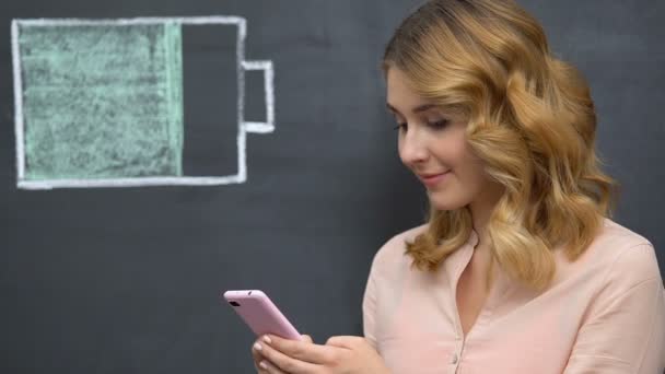 Woman surfing internet on mobile phone, battery symbol drawn, energy efficiency — Stock Video